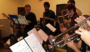 plusieurs musiciens dans une salle jouant de leur instrument devant leur partition