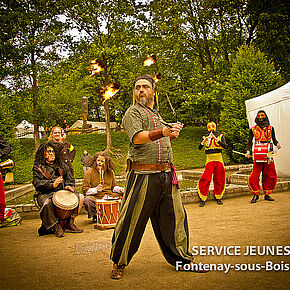 un homme en costume de type médiéval faisant tourner des boules de feu au bout d'une chaîne - Agrandir l'image, .JPG 382,5 KB (fenêtre modale)